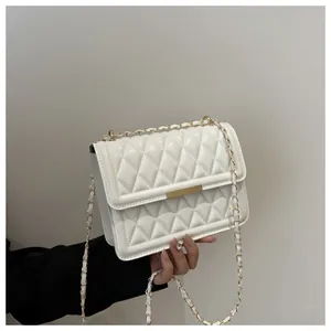 Detail of white quilted handbag featuring gold metal bar and elegant chain strap