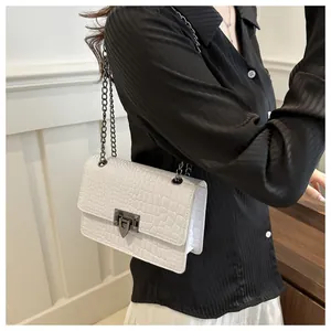 Détail du sac blanc motif crocodile avec sa chaîne en métal gris et boucle de fermeture