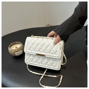 Detailed view of white quilted crossbody bag with gold metal clasp and chain strap