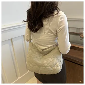 Detail view of heart-quilted crossbody bag in beige with soft nylon texture on model