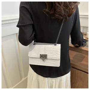 Détail du sac bandoulière blanc à motif crocodile avec chaîne métallique sur modèle