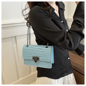 Détail d'un sac bleu clair à motif crocodile avec fermoir rétro et bandoulière en chaîne