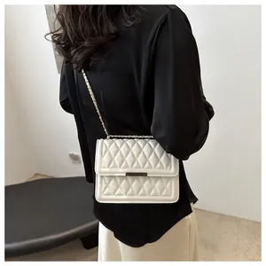 Detailed view of a white quilted crossbody bag with gold chain strap on a female model