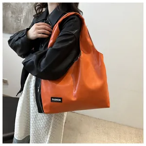Detail of the orange oil wax leather tote bag featuring a black fashion label accent