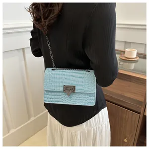 Détail du sac bandoulière bleu clair effet crocodile avec fermoir métallique sur modèle