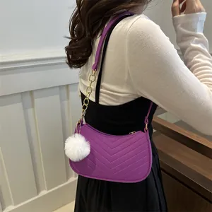 Purple quilted shoulder bag with gold chain strap and white faux fur ball charm