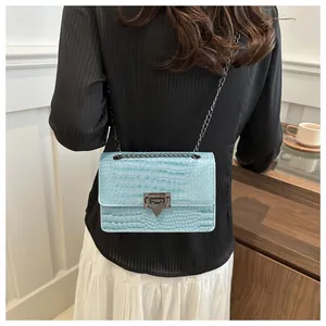 Détail du sac à main bleu clair motif crocodile avec chaîne et fermoir gris foncé