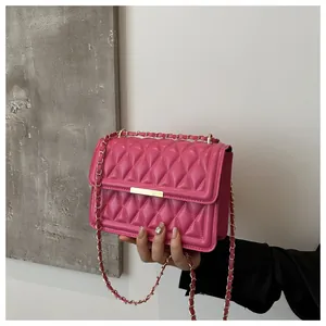 Close-up of bright pink quilted crossbody bag with gold chain strap and metal clasp