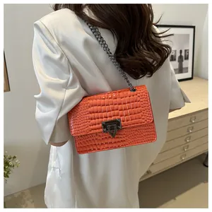 Détail du sac bandoulière orange à motif crocodile avec chaîne et fermoir métallique
