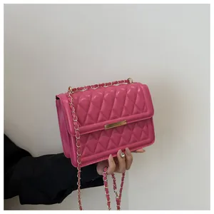 Close-up of fuchsia quilted crossbody bag with gold chain strap and metal lock detail