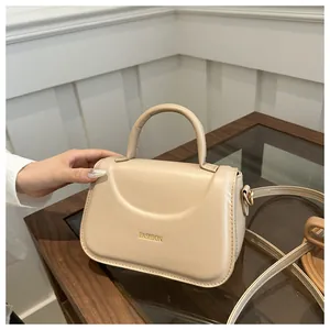 Dettaglio di una borsa beige chic con scritta Fashion dorata e finiture in metallo