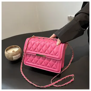 Close-up of bright pink quilted leather flap bag with gold clasp and chain strap detail