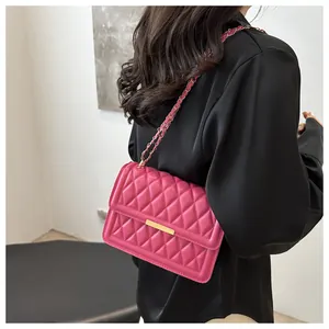 Hot pink quilted crossbody bag with gold buckle worn on shoulder by a model