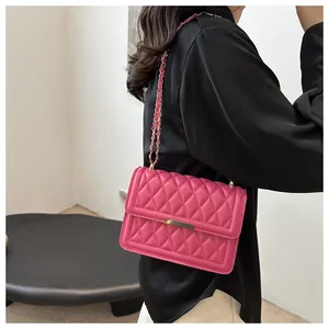 Close-up of quilted fuchsia crossbody bag with golden chain strap and metal clasp