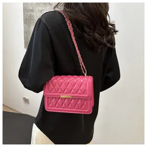 Detail of rose red quilted crossbody bag with gold chain strap and metallic clasp