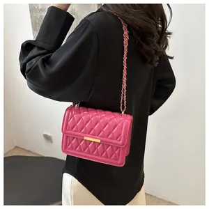 Detail of rose pink quilted leather bag with gold chain strap worn by a model