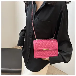 Close-up of quilted rhombic pattern and gold metal clasp on rose pink crossbody bag