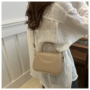 Dettaglio della borsa squadrata beige con scritta dorata fashion e pelle PU fine