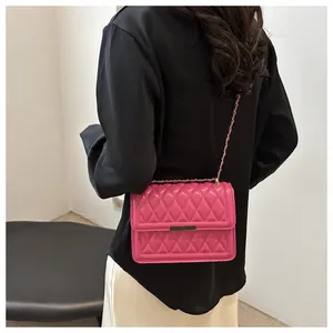 Detail of rose pink quilted crossbody bag with gold chain strap on black shirt