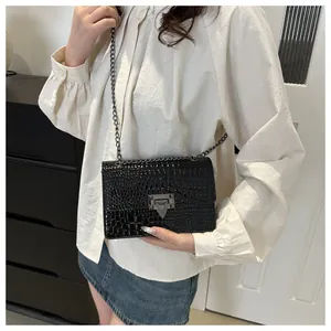 Détail du motif crocodile noir brillant et du fermoir en métal argenté du sac à chaîne