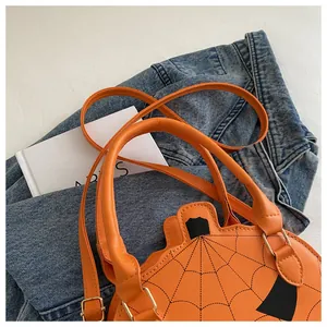 Close-up of bright orange pumpkin shaped crossbody bag with spider web stitching on denim
