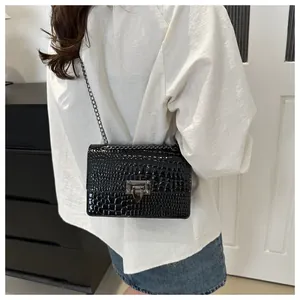 Détail du sac bandoulière noir motif crocodile avec chaîne en métal et fermoir boucle