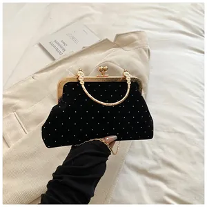 Close-up of vintage black velvet evening bag with gold metal frame and pearl details