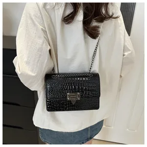 Mannequin portant un sac bandoulière noir motif crocodile avec boucle en métal noir