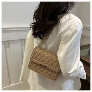 Close-up of quilted khaki leather texture and gold chain strap on small square bag