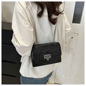 Sac à bandoulière en similicuir crocodile noir avec chaîne et fermoir argenté sur modèle