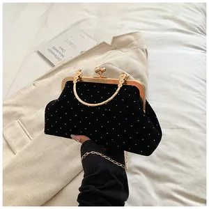 Detail of vintage black velvet evening bag with white polka dots and gold metal handle