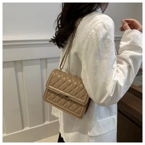 Detailed side view of beige quilted crossbody bag with metal chain strap and flap closure