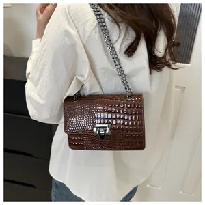Détail du sac bandoulière en similicuir marron foncé avec motif croco et chaîne argentée