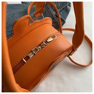 Detail of bright orange creative handbag featuring double metallic zippers and unique texture