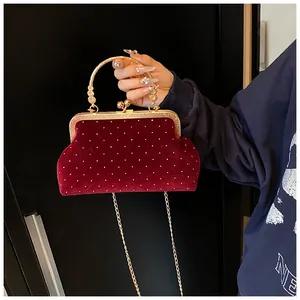 Close-up of burgundy velvet evening clutch with silver rhinestones and gold clasp