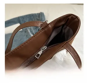 Detailed close-up of smooth metal zipper closure on the brown leather tote bag