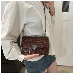 Détail du sac marron motif crocodile avec bandoulière chaîne et fermoir rotatif flèche