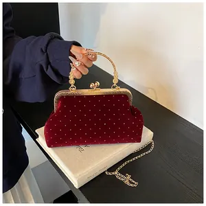 Detailed view of luxury deep red velvet handbag with silver polka dots and gold chain strap