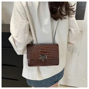 Détail du sac marron foncé à motif crocodile avec chaîne en argent et boucle carrée