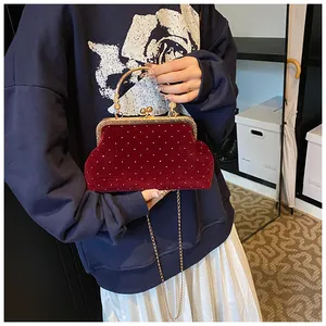 Detail of burgundy velvet clutch bag with vintage metal handle and sparkling rhinestone dots