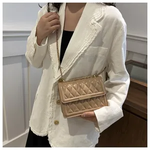 Detail of beige quilted flap bag with gold chain strap worn with white tweed jacket