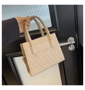 Gros plan d'un sac à main beige avec texture gaufrée en losange et poignées élégantes