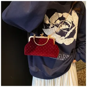 Detail of red velvet evening bag with pearls and golden chain strap on a model