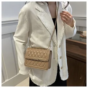 Quilted beige crossbody bag with gold chain strap styled on a white blazer outfit