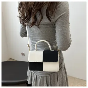 Dettaglio del patchwork a contrasto della piccola borsa a mano in pelle bianca e nera