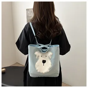 Detail view of light blue tote bag featuring a plush schnauzer patch and versatile straps