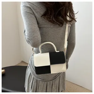 Dettaglio di una borsa chic a contrasto bianco e nero indossata da una modella per stile