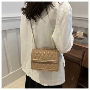 Detail of khaki quilted crossbody bag featuring a gold metal lock and chain strap