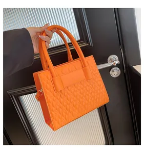 Détail du sac à main orange avec texture matelassée et anneaux dorés en métal