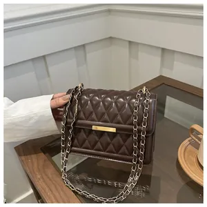 Detail of deep brown quilted crossbody bag with gold buckle on a cafe table